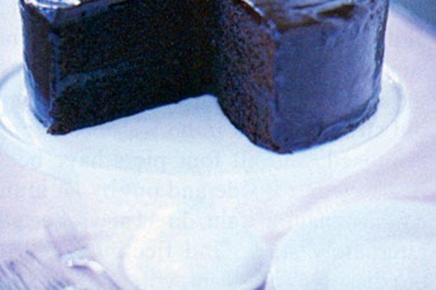 A low-quality photo of a chocolate cake on a cake stand, with the top of the cake cut off by poor cropping.